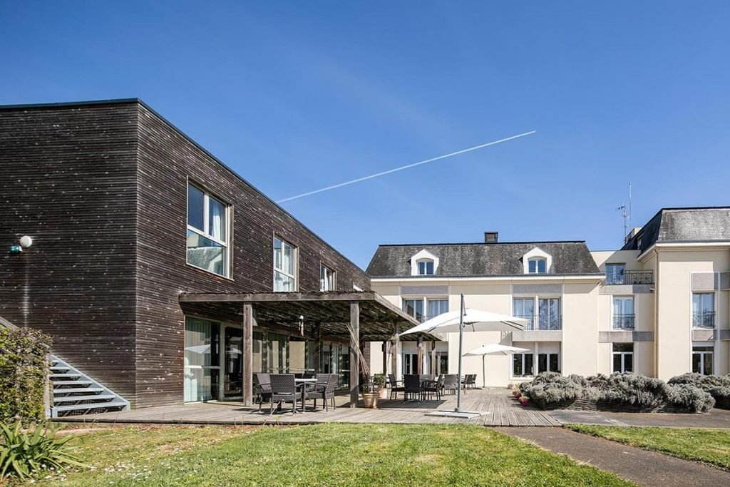 Terrasse en bois avec tables sous tonnelle et chemins aménagés dans le jardin pour faciliter les déplacements